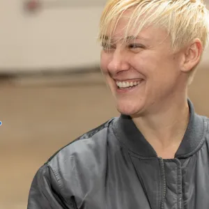 Woman with short blonde hair looking to her right, smiling.