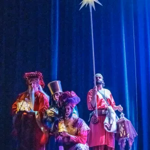 four men clumped together.  One holds a star lamp high above their heads.