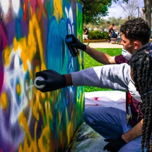 Two college students spray painting a wall