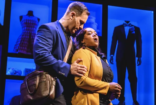 Tall man with hand on woman's bicep.  His nose is close to her hair.